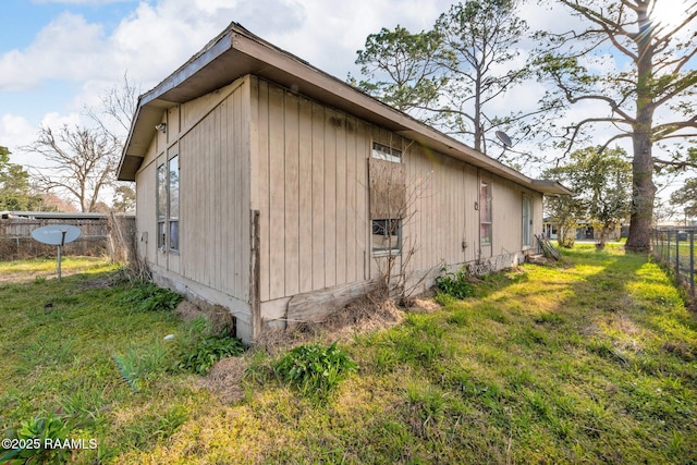 view of side of home with a yard and fence