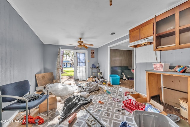 living room with visible vents, wood walls, a ceiling fan, and crown molding