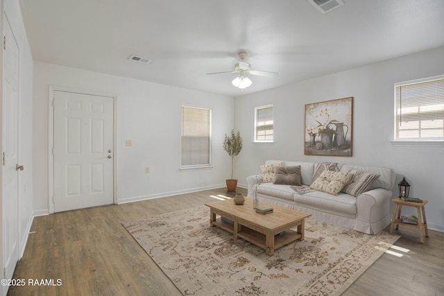 living area with a ceiling fan, visible vents, baseboards, and wood finished floors