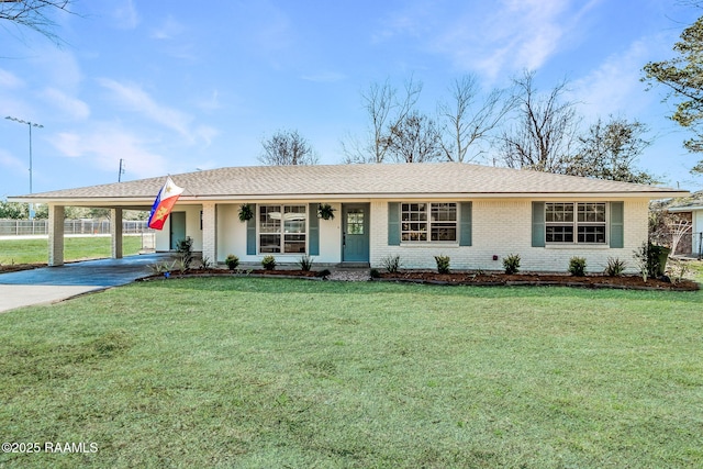 ranch-style house featuring brick siding, concrete driveway, fence, a carport, and a front lawn