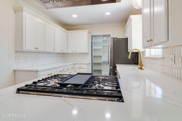 kitchen featuring gas cooktop, white cabinets, light stone countertops, and freestanding refrigerator