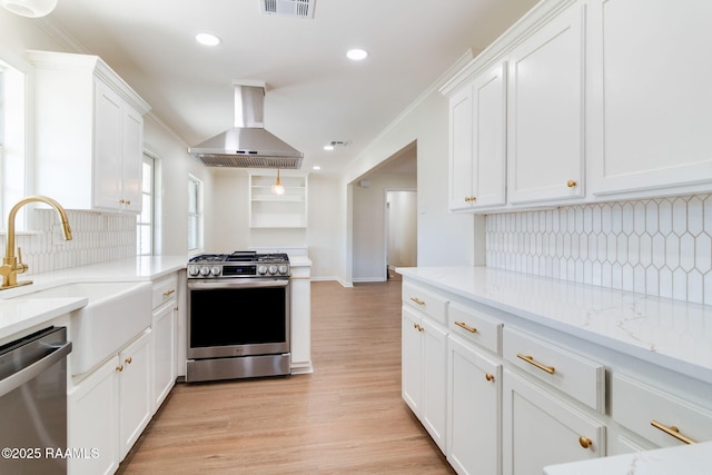 kitchen featuring a sink, appliances with stainless steel finishes, white cabinets, and wall chimney range hood