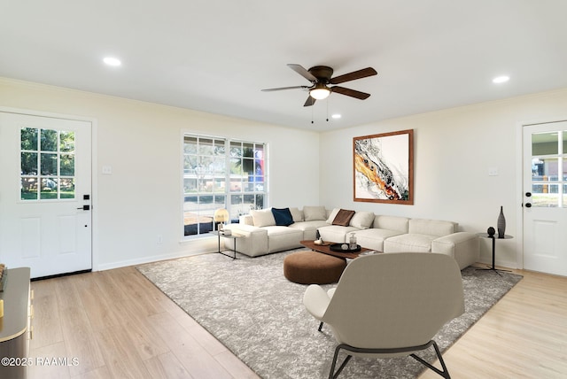 living area with plenty of natural light, crown molding, and light wood finished floors