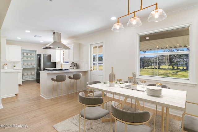 dining space featuring crown molding, plenty of natural light, recessed lighting, and light wood-type flooring