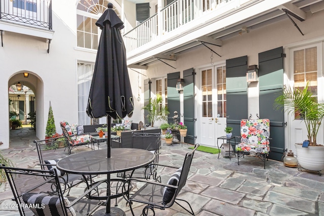 view of patio / terrace featuring outdoor dining space, french doors, and a balcony