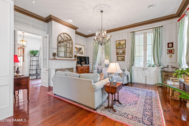 living area with a chandelier, a decorative wall, ornamental molding, and wood finished floors