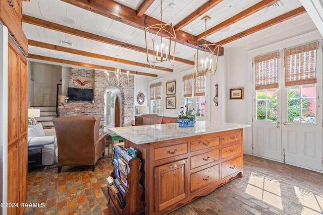 kitchen featuring arched walkways, brick floor, open floor plan, hanging light fixtures, and beamed ceiling