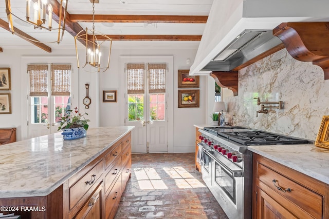 kitchen featuring range with two ovens, brick floor, backsplash, brown cabinetry, and under cabinet range hood