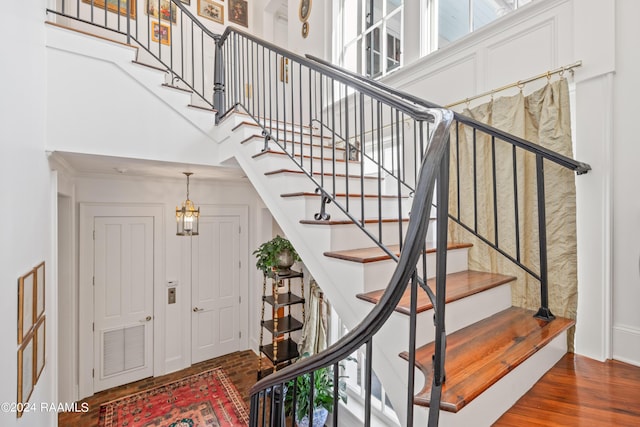 stairway with a high ceiling, wood finished floors, and visible vents