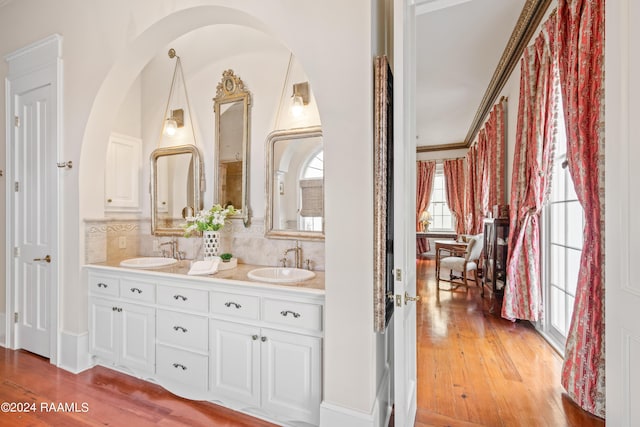 full bathroom featuring double vanity, a sink, backsplash, and hardwood / wood-style flooring