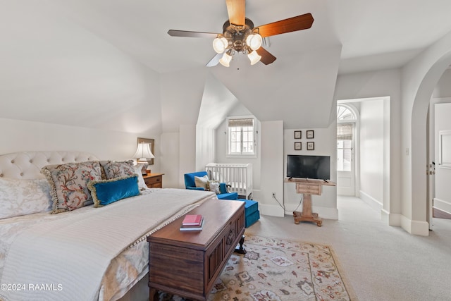 carpeted bedroom featuring vaulted ceiling, arched walkways, a ceiling fan, and baseboards