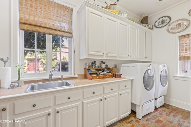 laundry room with a sink, baseboards, ornamental molding, cabinet space, and washing machine and clothes dryer