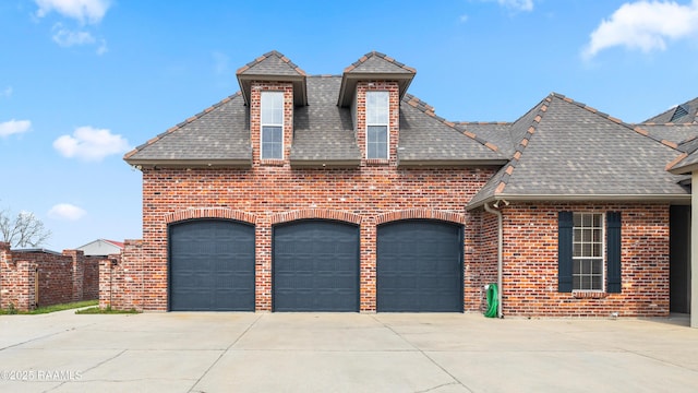 view of front facade with an attached garage, driveway, roof with shingles, and brick siding