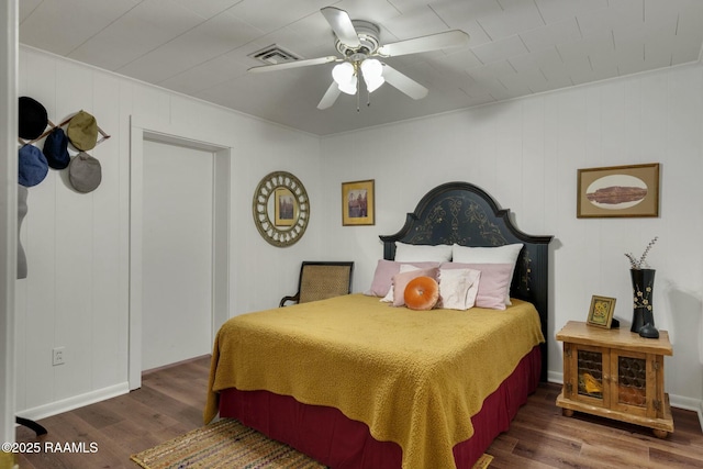 bedroom featuring a ceiling fan, visible vents, and wood finished floors