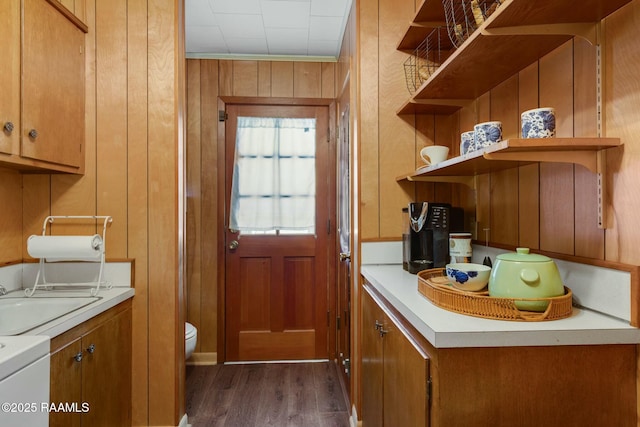 interior space featuring brown cabinetry, light countertops, a sink, and wood walls