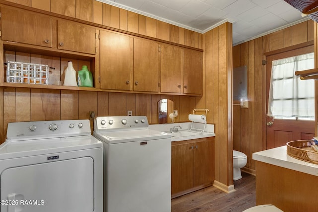 laundry area featuring laundry area, wooden walls, washer and dryer, and wood finished floors