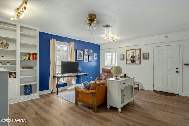 living room featuring baseboards, wood finished floors, visible vents, and a ceiling fan