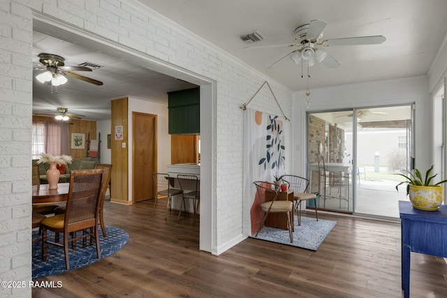 interior space with brick wall, visible vents, dark wood-type flooring, and ornamental molding