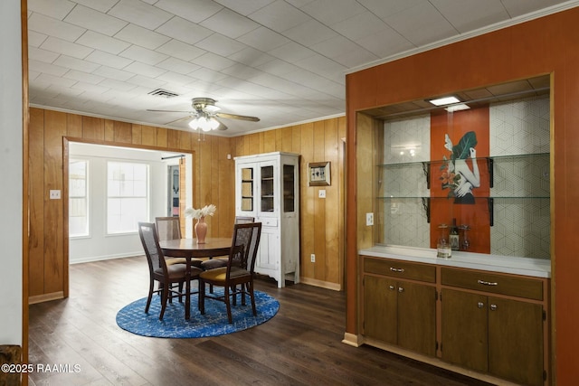 dining area featuring ornamental molding, dark wood-style flooring, visible vents, and a ceiling fan