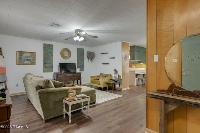 living room with visible vents, ceiling fan, baseboards, and wood finished floors