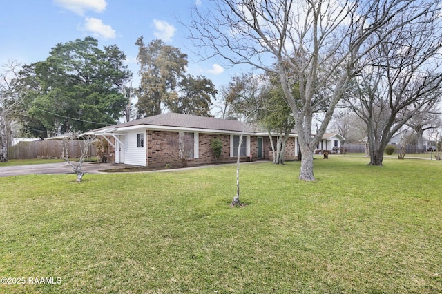 view of front of property featuring brick siding, fence, driveway, and a front lawn