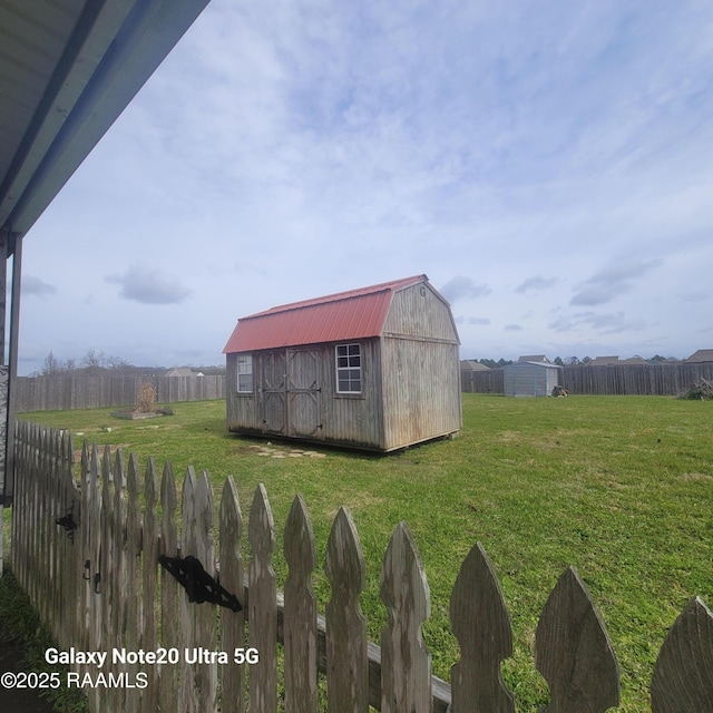 view of yard featuring a storage shed, fence, and an outbuilding