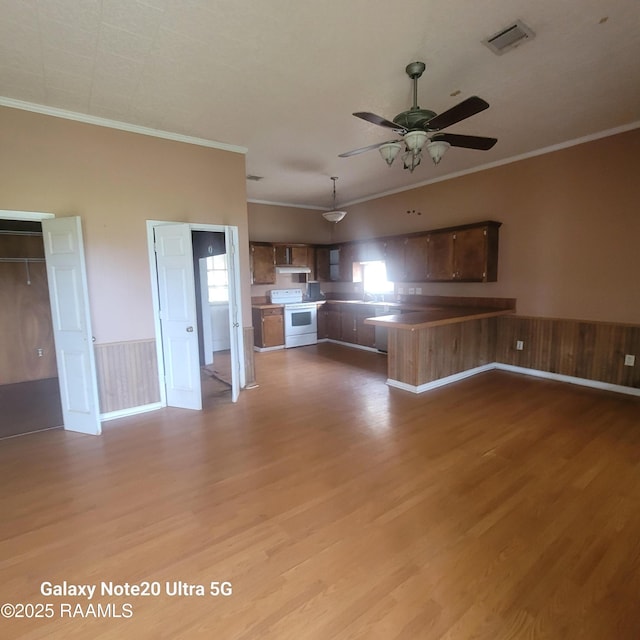 unfurnished living room featuring a wainscoted wall, visible vents, light wood finished floors, and ornamental molding