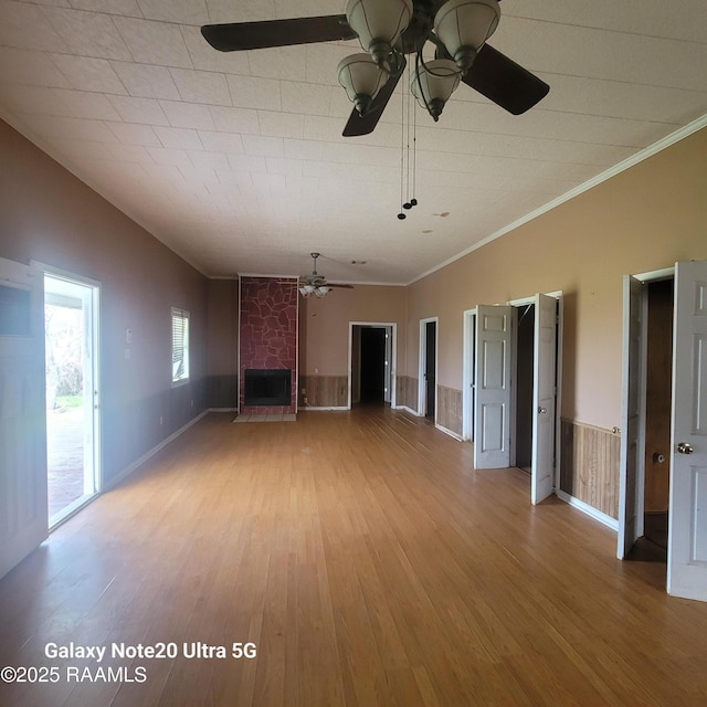 unfurnished living room featuring lofted ceiling, a large fireplace, ceiling fan, and wood finished floors