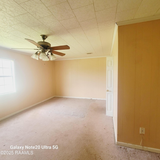 empty room with wood walls, a ceiling fan, and carpet flooring