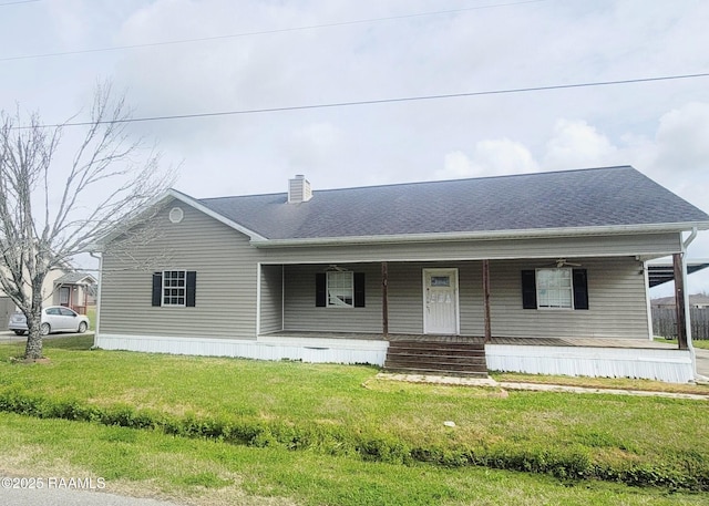 manufactured / mobile home featuring roof with shingles, a porch, a front lawn, and a chimney