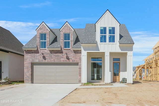 view of front of house featuring board and batten siding, brick siding, a shingled roof, and driveway