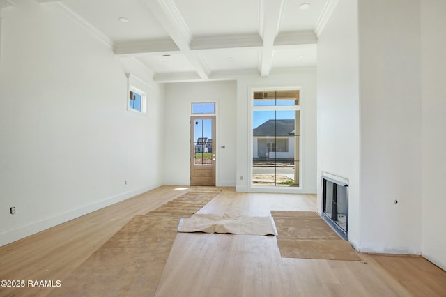 interior space with beam ceiling, coffered ceiling, wood finished floors, a fireplace, and baseboards