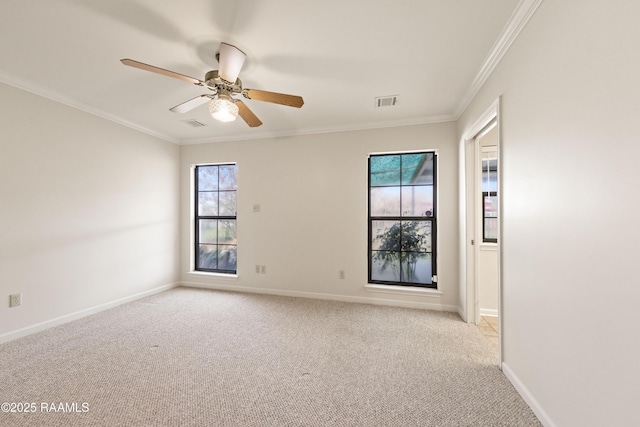 empty room featuring a ceiling fan, crown molding, light colored carpet, and baseboards