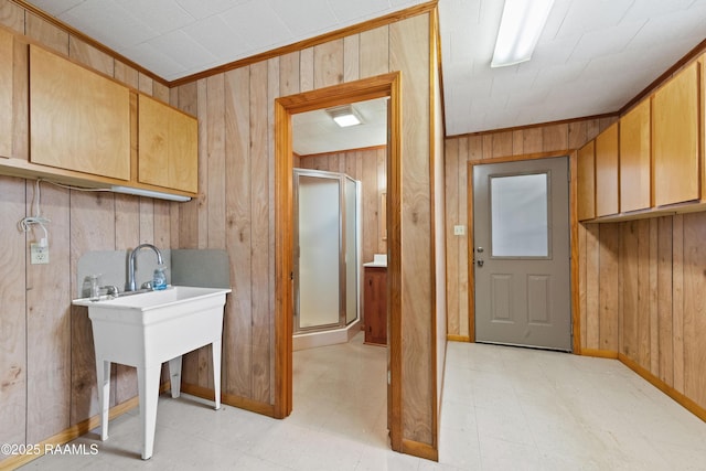 laundry room featuring crown molding, wooden walls, light floors, and baseboards