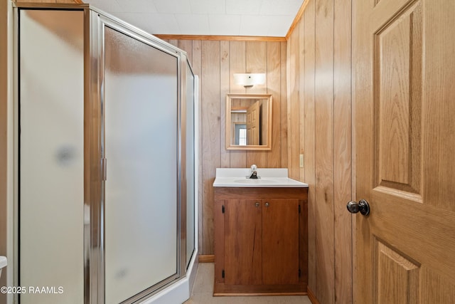bathroom with a shower stall, vanity, and wood walls