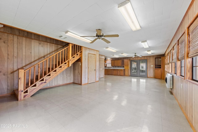 interior space with visible vents, stairway, french doors, wood walls, and light floors