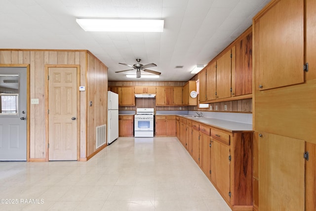 kitchen with visible vents, under cabinet range hood, light countertops, white appliances, and a sink