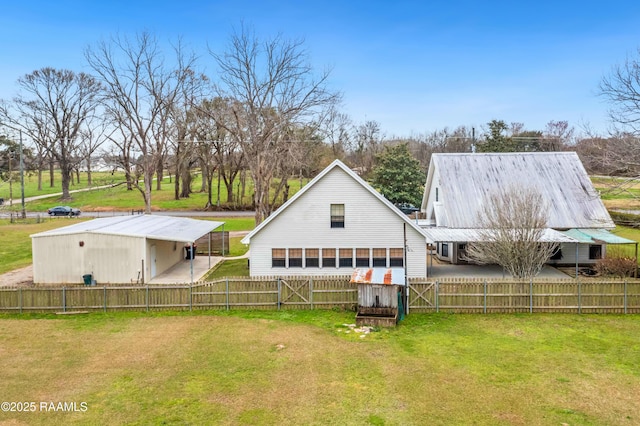 rear view of property with an outbuilding, driveway, fence, a yard, and metal roof