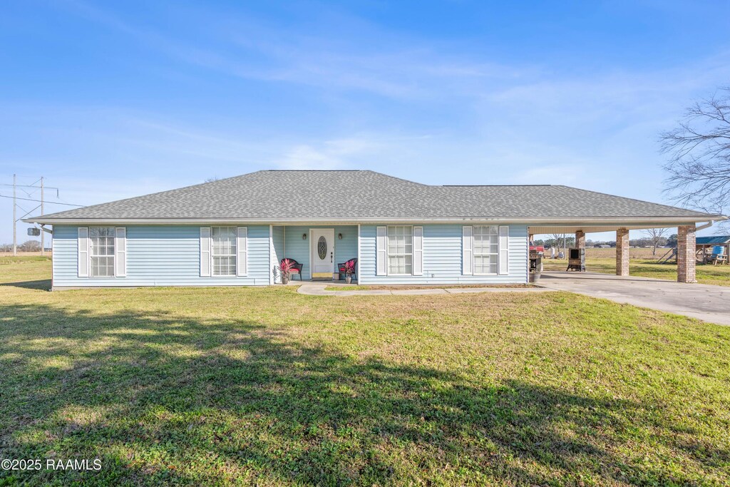 single story home with a carport, roof with shingles, a front yard, and driveway