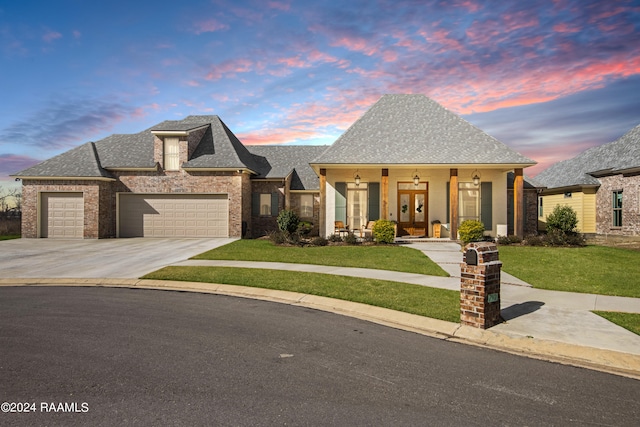 view of front facade featuring a garage, driveway, a shingled roof, covered porch, and a front lawn