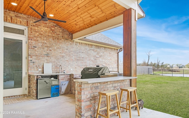 view of patio / terrace with an outdoor kitchen, a sink, fence, a ceiling fan, and grilling area