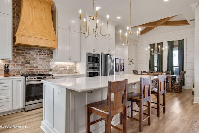 kitchen with light wood-style flooring, stainless steel appliances, a kitchen island, backsplash, and custom range hood