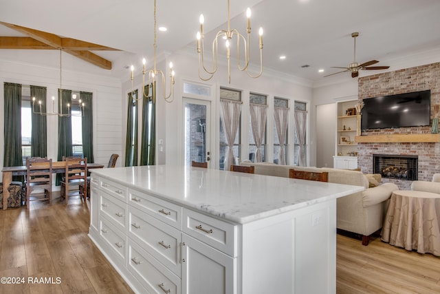 kitchen featuring ornamental molding, light wood-type flooring, a fireplace, and white cabinets