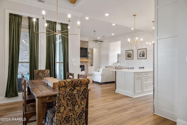 dining room featuring light wood-style flooring, recessed lighting, ceiling fan with notable chandelier, a fireplace, and ornamental molding