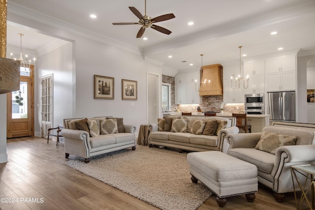 living area featuring crown molding, ceiling fan with notable chandelier, wood finished floors, and recessed lighting