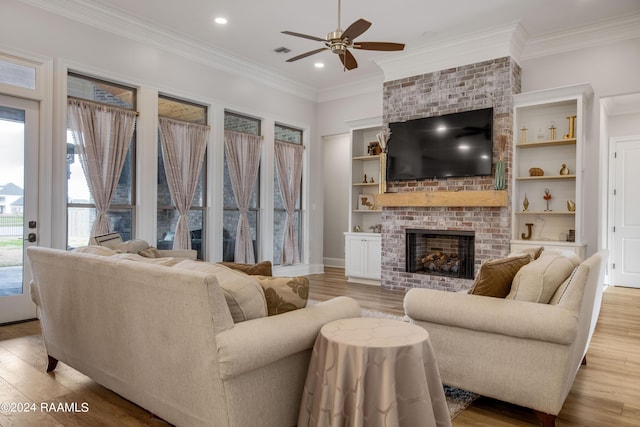 living area with ornamental molding, light wood-type flooring, recessed lighting, and a brick fireplace