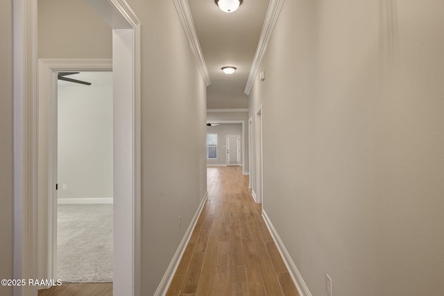 corridor featuring ornamental molding, baseboards, and wood finished floors