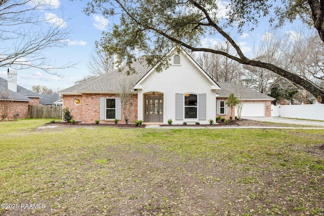 view of front of home with an attached garage, a front yard, fence, and brick siding