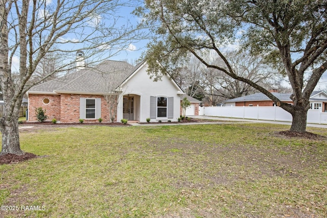 view of front of property with brick siding, a chimney, a shingled roof, a front yard, and fence