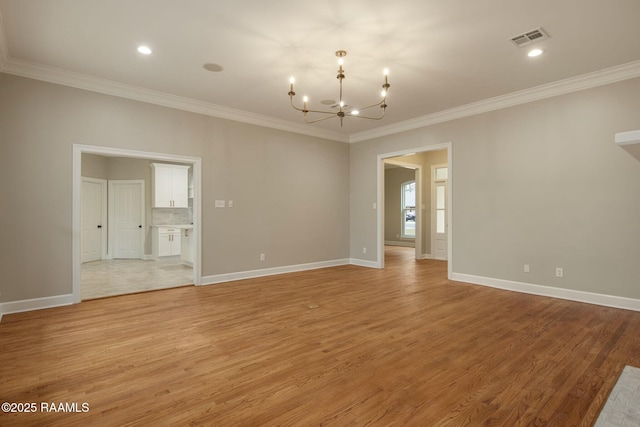 empty room with light wood-style flooring, visible vents, and an inviting chandelier